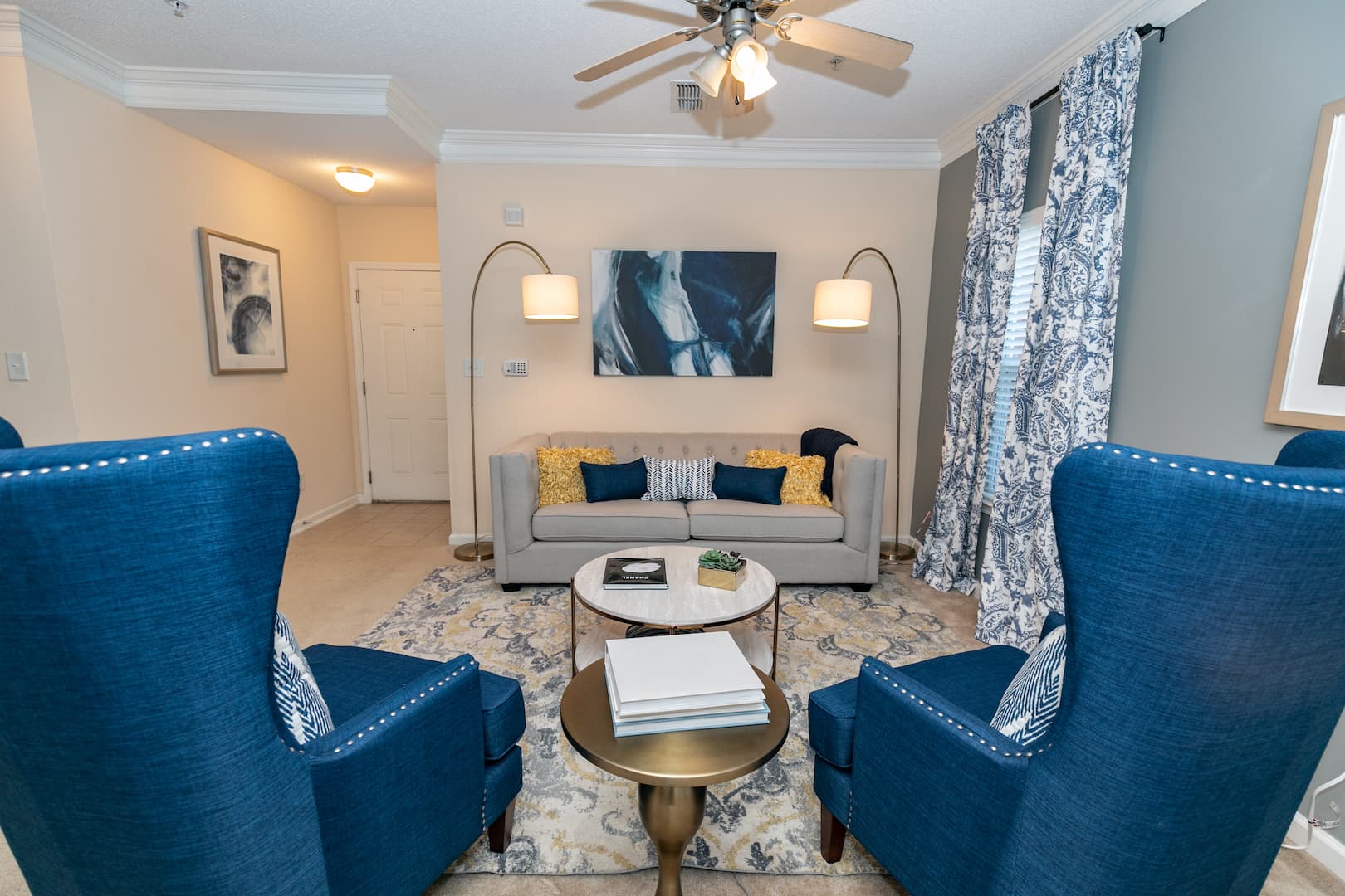 model living room with ceiling fan, modern rug, crown molding and ample lighting