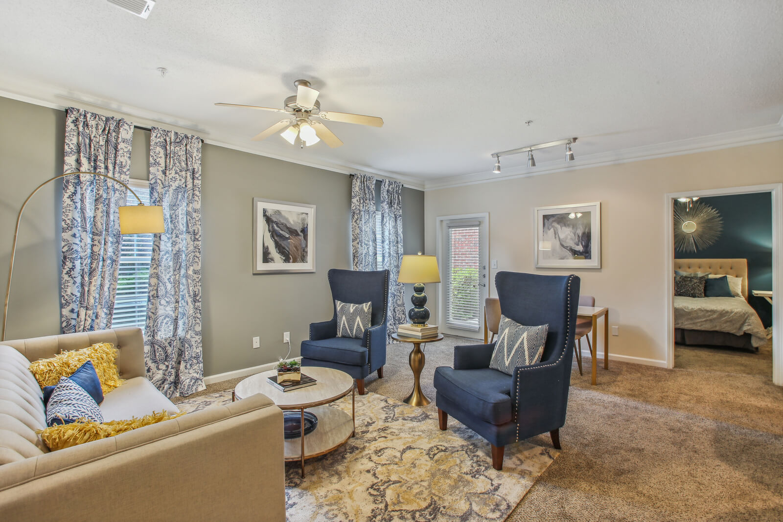 model living room with ceiling fan and carpet