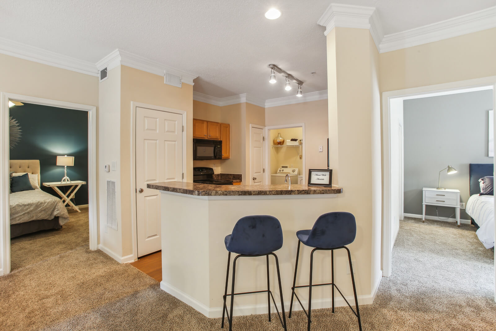 model kitchen with breakfast bar and ample lighting, showing two bedrooms, one on each side of kitchen