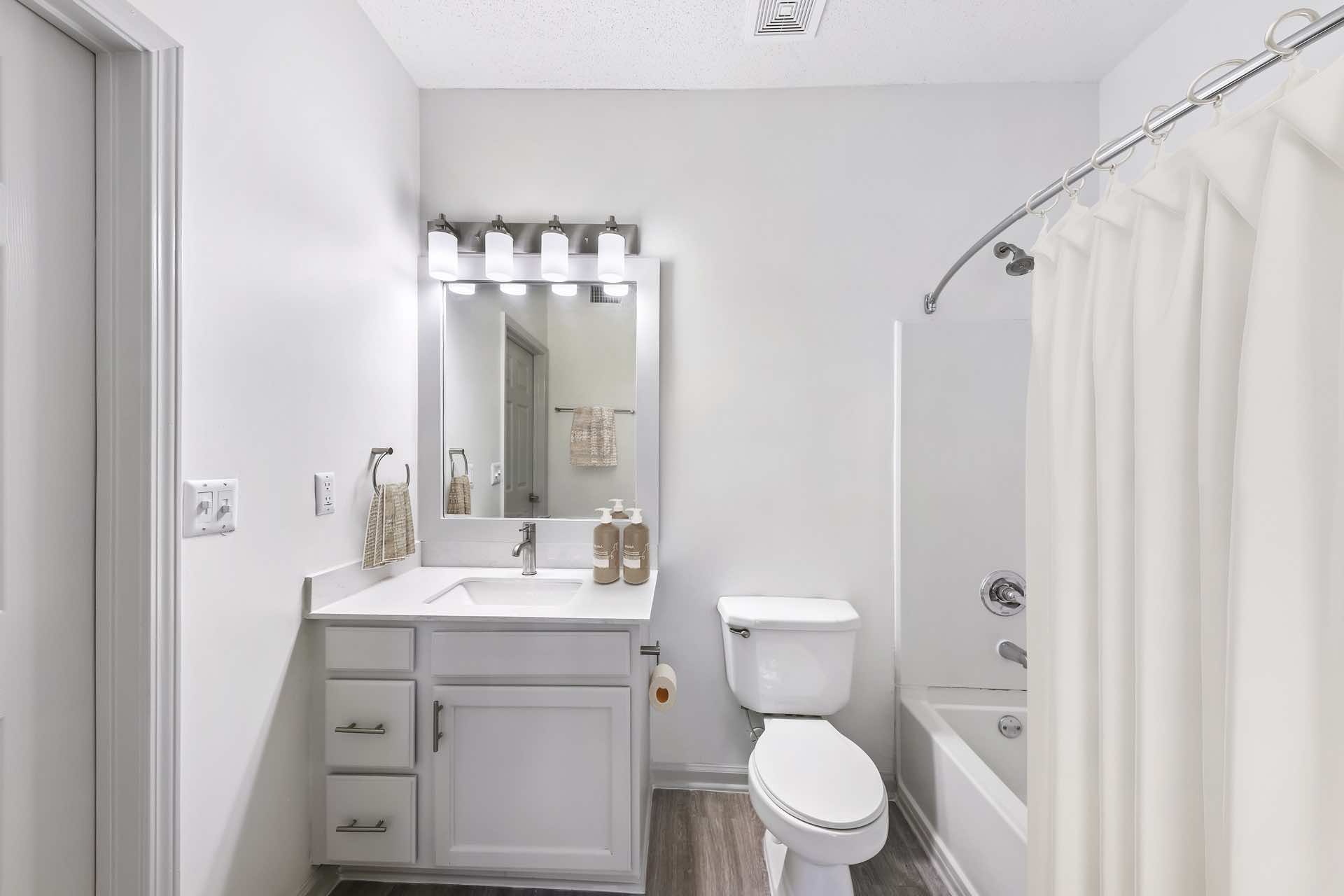 bathroom with wood-style flooring, modern lighting and curved shower rod