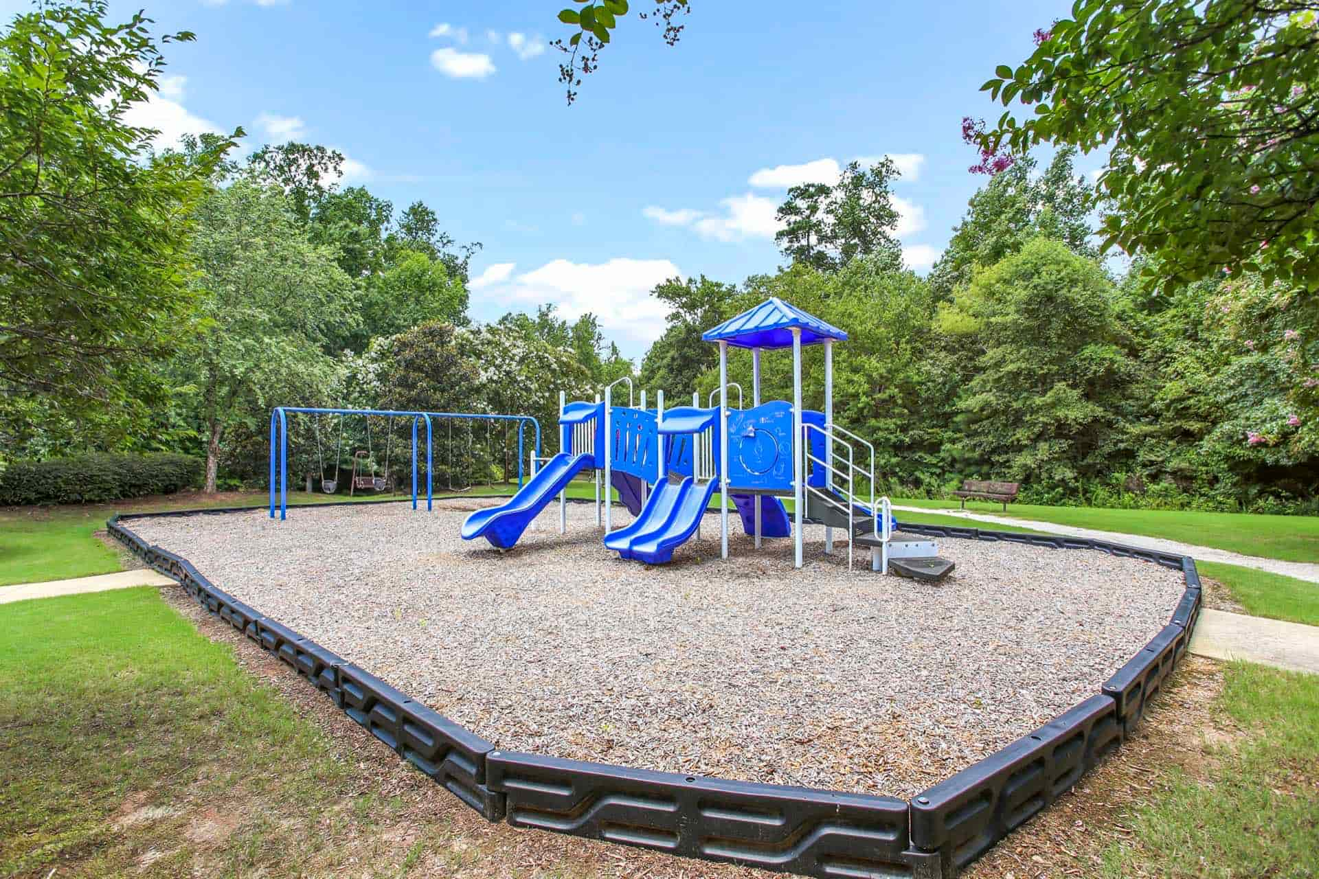 playground surrounded by grass area and green trees