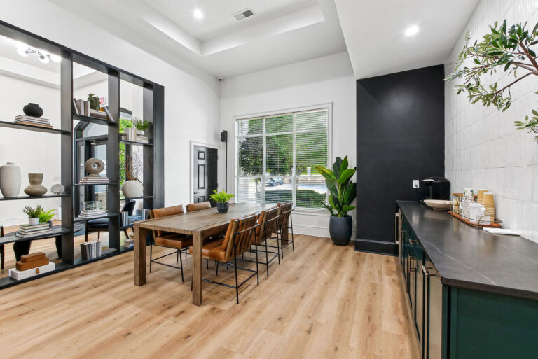 Resident lounge with hardwood-style floors , large table with chairs and coffee bar.